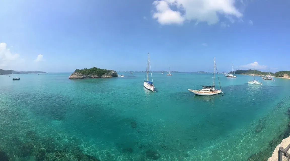 透きとおった青緑の海に、小さな島とヨットが浮かぶ風景